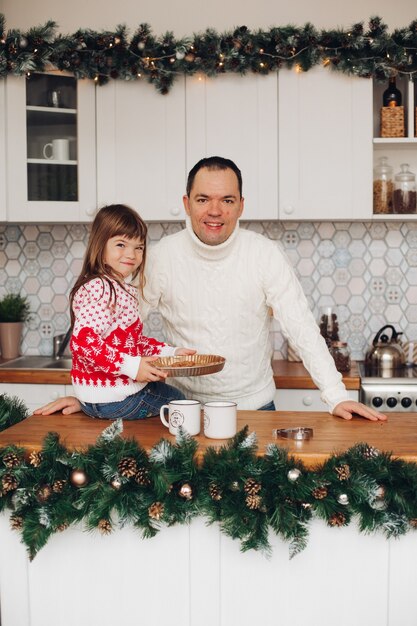 Padre amoroso feliz con hija sentada en la cocina decorada