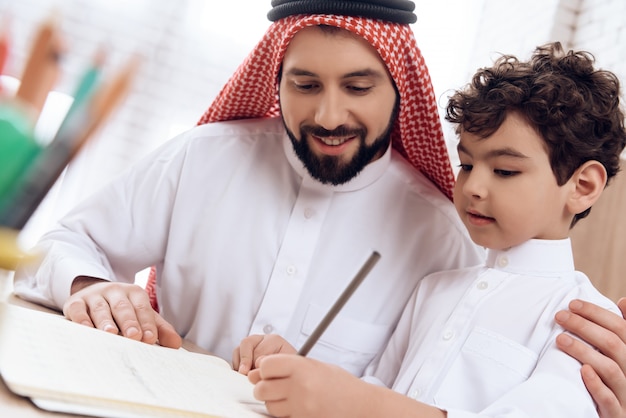 El padre árabe enseña al pequeño hijo de las letras de ortografía.