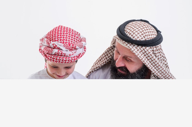 Padre árabe con hijo sosteniendo cartel blanco y sacando la lengua foto de stock