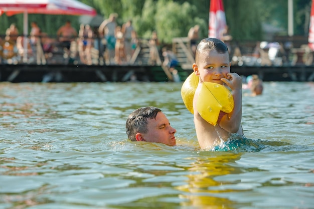Padre arrojando a su hijo al agua divirtiéndose en actividades de ocio de verano