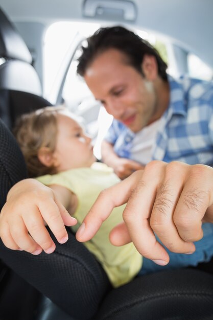 Padre asegurando a su bebé en la silla de auto