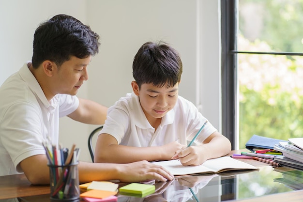 Padre asiático ayuda a su hijo a hacer sus tareas para la escuela xChild estudian juntos concepto de educación en casa recibiendo ayuda de tareas del padre