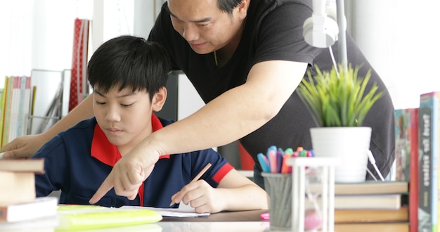 Padre asiático e hijo haciendo la tarea en casa.