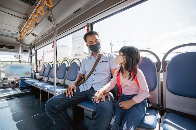 Padre asiático llevando a su hija a la escuela en autobús de transporte público