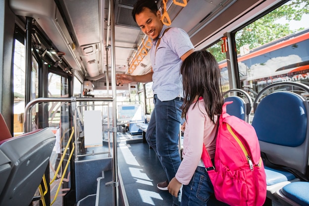Padre asiático llevando a su hija a la escuela en autobús de transporte público