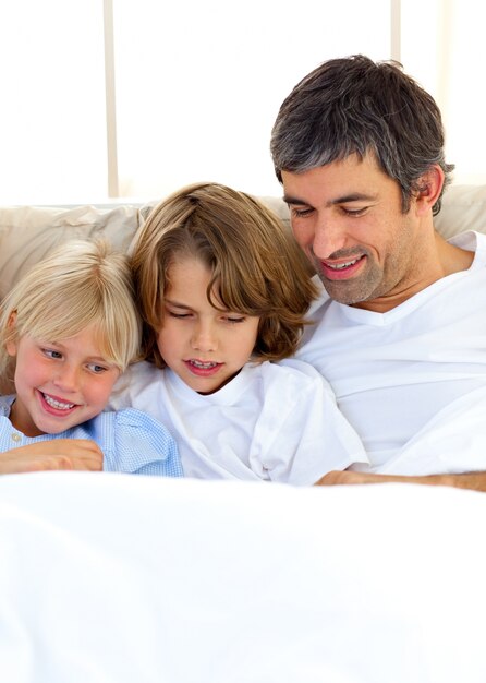 Foto padre atento y sus hijos leyendo el libro