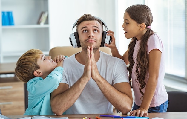 El padre en auriculares sentado con niños en el escritorio