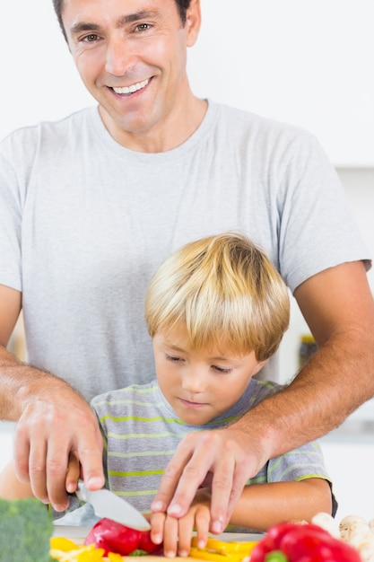 Padre ayudando a hijo a cortar verduras