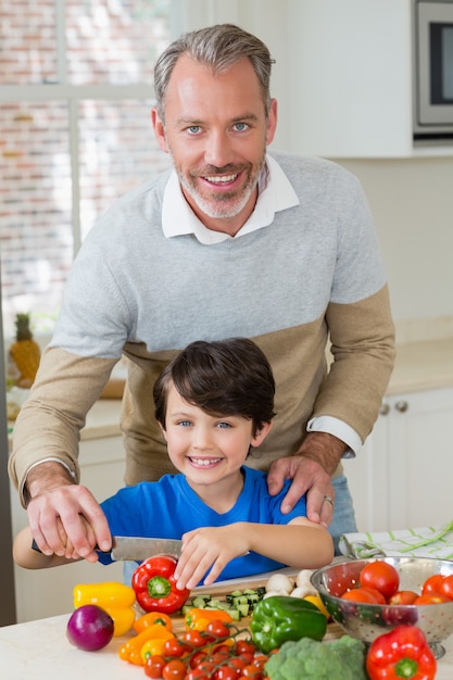 Padre ayudando a un hijo a picar el pimiento rojo en la cocina