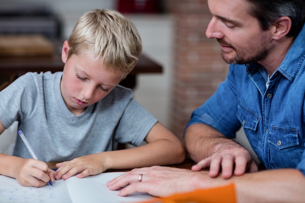 Padre ayudando a hijo con su tarea en la cocina