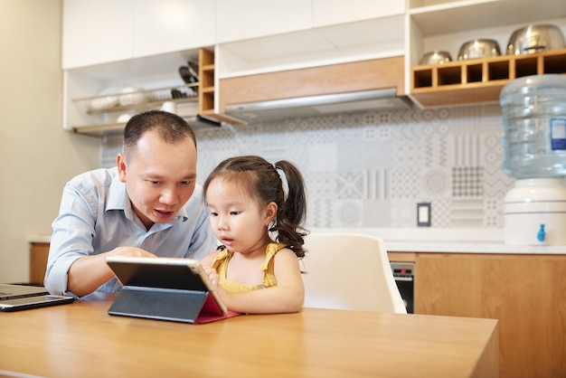 Padre ayudando a su hija a resolver la tarea en la aplicación educativa en línea