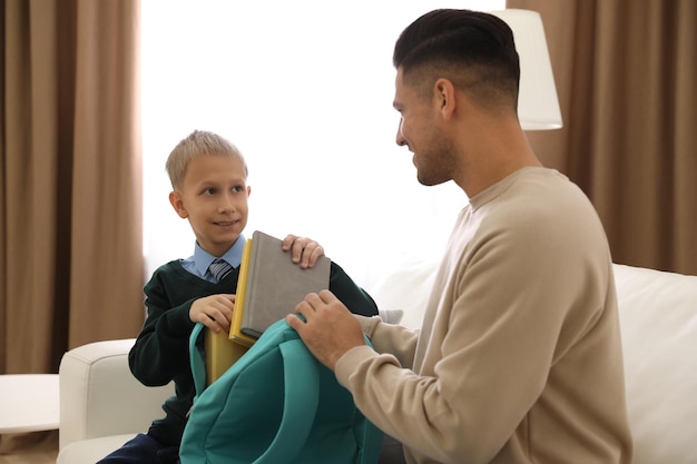 Padre ayudando a su hijo pequeño a prepararse para la escuela en casa