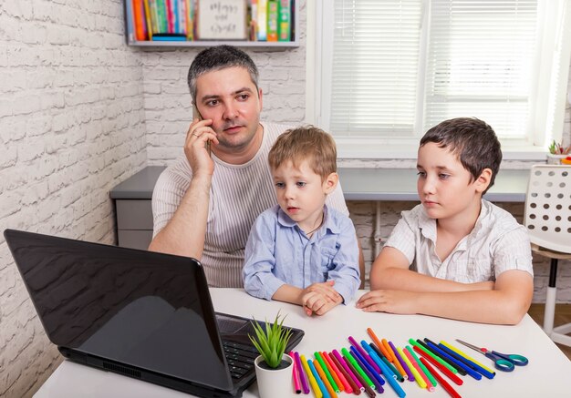 Padre ayudando a sus hijos en la tarea en línea