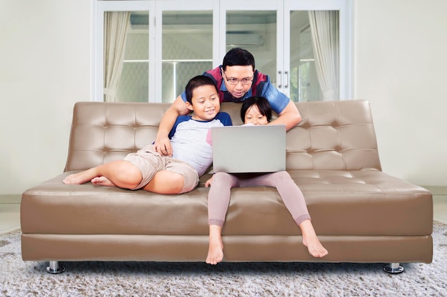 Padre ayudando a sus hijos a usar una laptop en casa