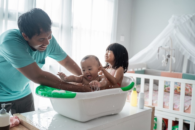 Padre bañando a sus hijos