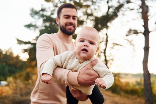 Padre barbudo jugando con su hijo al aire libre durante el día soleado al aire libre