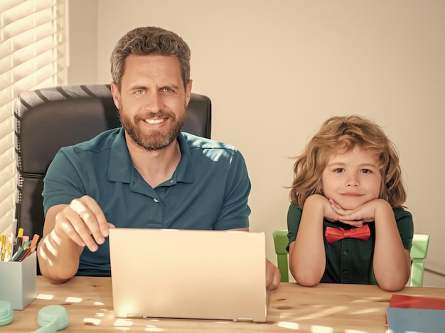 Padre barbudo o tutor privado de la escuela enseñando a un hijo con una computadora portátil moderna para estudiar en línea