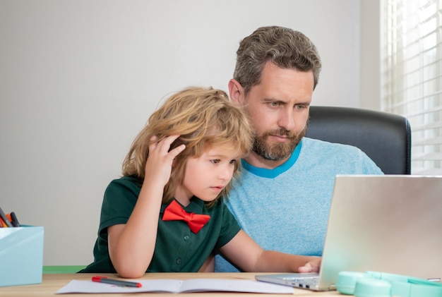 Padre barbudo o tutor privado de la escuela enseñando a un hijo con un seminario web moderno para portátiles