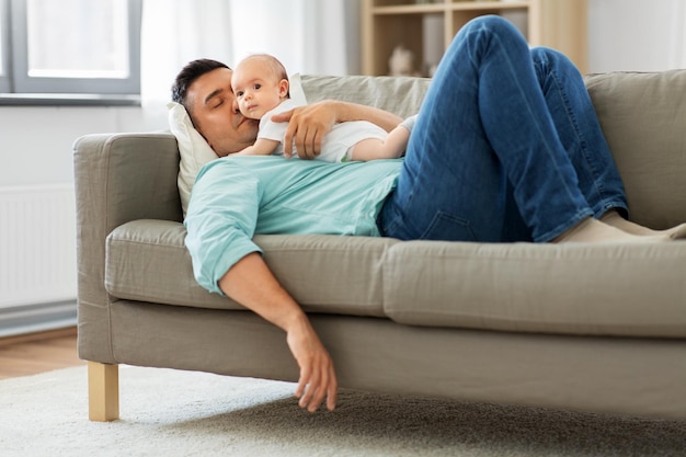 padre con el bebé durmiendo en el sofá en casa