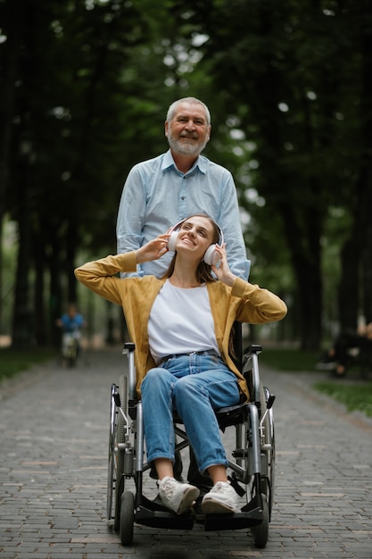 Padre camina con hija discapacitada en silla de ruedas