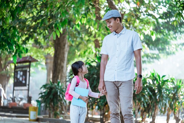 Padre camina con su hijo a la escuela por la mañana