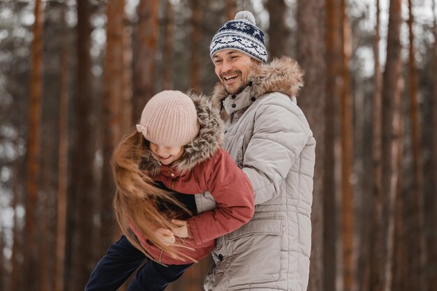 Padre camina con su pequeña hija en el bosque de invierno Familia feliz padre e hija en la naturaleza Concepto del día del padre