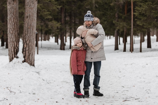 Padre camina con sus pequeñas hijas en el bosque de invierno