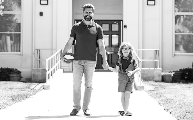 Padre caminando hijo a la escuela padre y alumno de la escuela primaria colegial con mochila