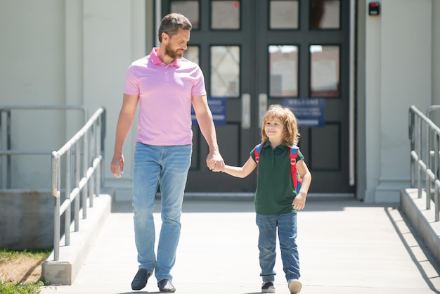 Padre caminando con su hijo a la escuela Padre y alumno de un colegial de escuela primaria con mochila Padre llevando a su hijo a la escuela Alumno de la escuela primaria va a estudiar con una mochila al aire libre