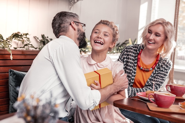 Padre cariñoso. Agradable hombre encantado abrazando a su hija mientras la felicitaba por su cumpleaños