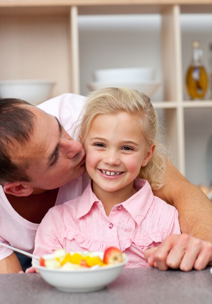 Padre cariñoso comiendo fruta con su hija