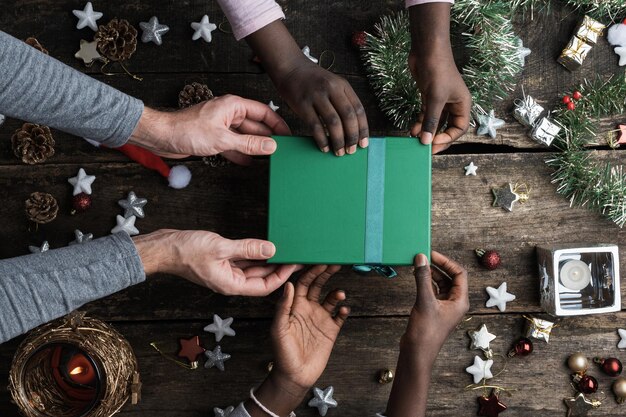 Padre caucásico y sus hijas de color negro con caja de regalo navideña