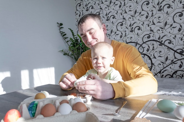 Un padre celebra la Pascua con su hijo pequeño. Baten huevos, comen huevos y desayunan. Papá le enseña al niño.