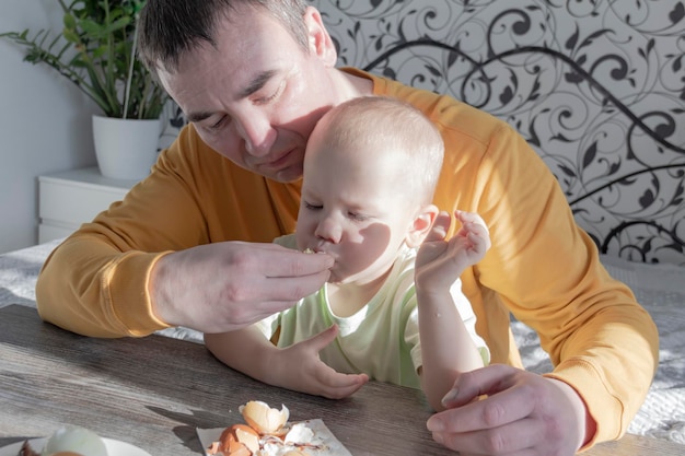 Un padre celebra la Pascua con su hijo pequeño. Baten huevos, comen huevos y desayunan. Papá le enseña al niño.