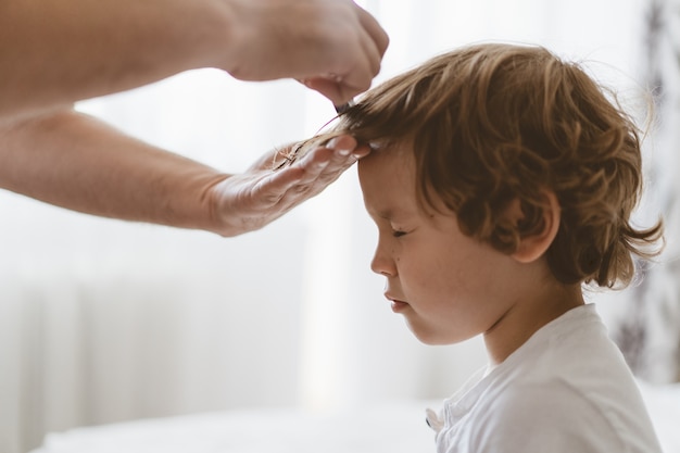 Foto el padre le corta el pelo a su hijo en la habitación. familia durante la cuarentena