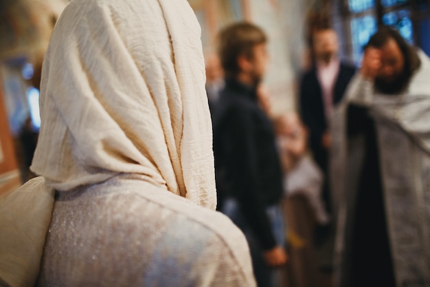 Foto padre cristão ortodoxo e paroquiano orando na igreja.