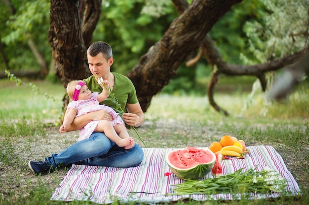 El padre le da a su pequeña hija una flor Picnic en el parque