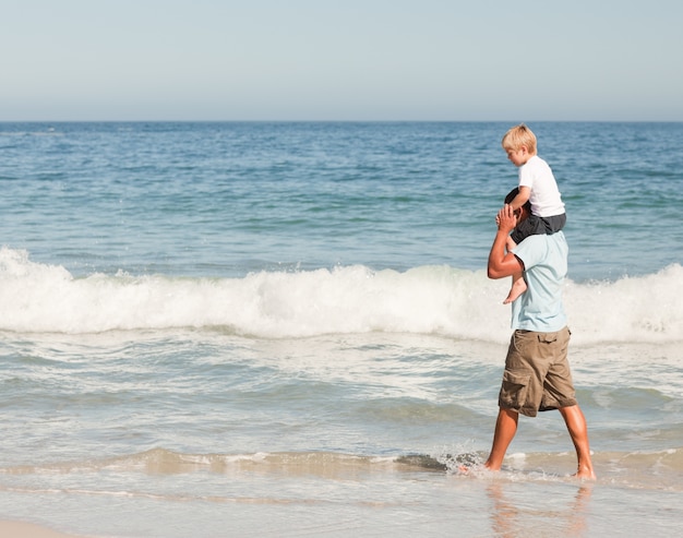 Padre dando hijo a cuestas en la playa