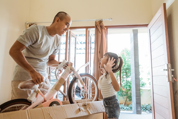 Padre desembalaje y levantando una bicicleta con su hija feliz