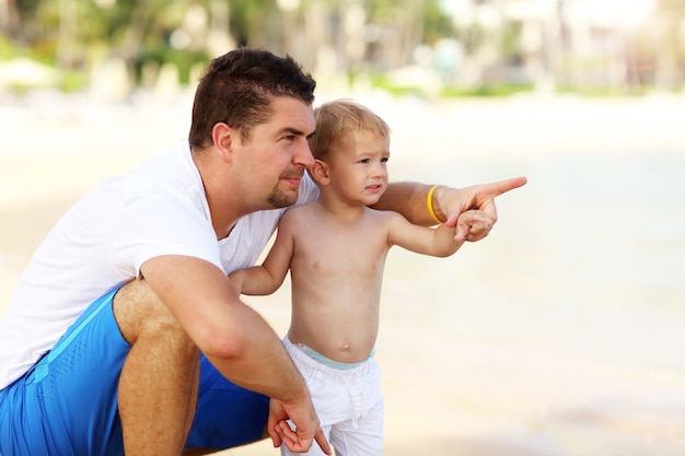 padre divirtiéndose en la playa con su pequeño hijo