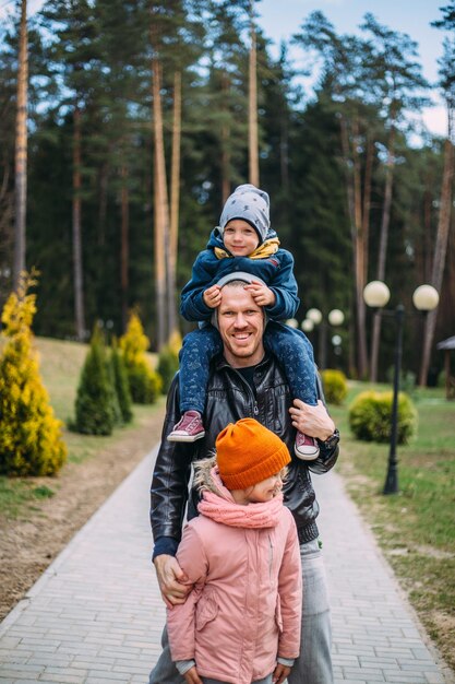 Padre y dos hijos caminan en la naturaleza en otoño pasan tiempo juntos divirtiéndose