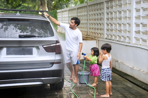 Padre y dos hijos lavan un coche en casa