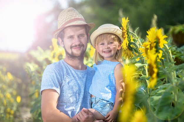 Padre e hija se abrazan en el campo de girasoles mirando a la cámara