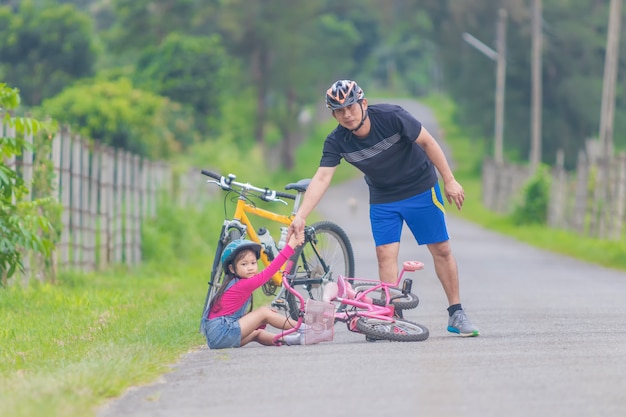 Padre e hija asiáticos andar en bicicleta en la calle.