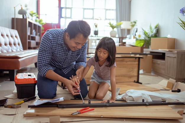 padre e hija asiáticos ensamblando muebles nuevos en su casa juntos