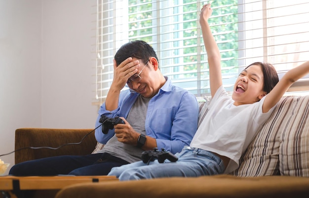 Padre e hija asiáticos jugando videojuegos en casa Personas haciendo actividades y conceptos familiares