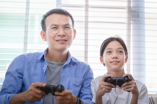 Padre e hija asiáticos jugando videojuegos en casa Personas haciendo actividades y conceptos familiares