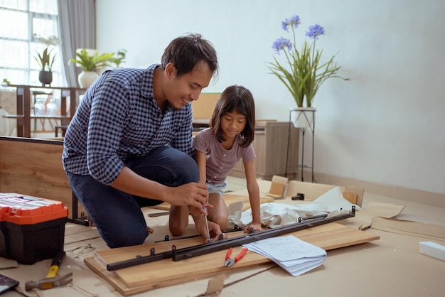 Padre e hija asiáticos montando muebles nuevos en su casa