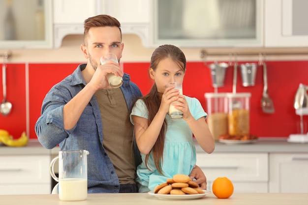 Padre e hija bebiendo leche fresca en la cocina