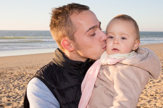 Padre e hija se besan en la playa al atardecer
